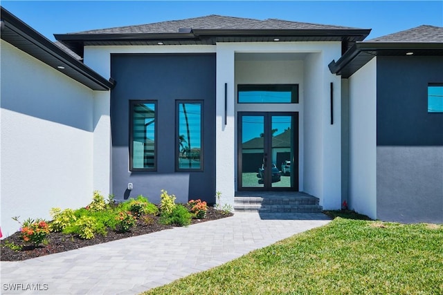 view of exterior entry featuring stucco siding, roof with shingles, and french doors