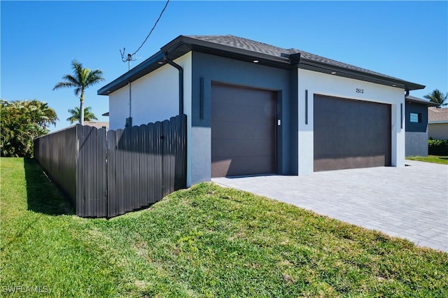 view of home's exterior with a garage, driveway, stucco siding, and fence