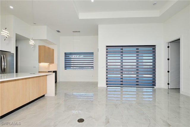 interior space with modern cabinets, light brown cabinetry, light countertops, and freestanding refrigerator