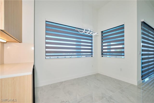 spare room with marble finish floor and baseboards