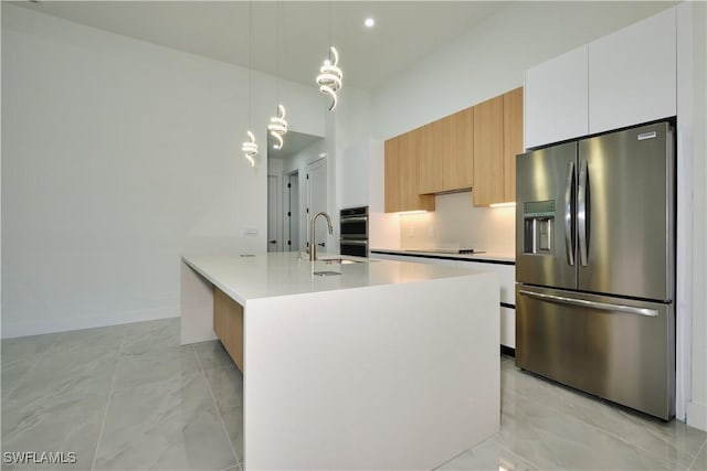 kitchen with a sink, modern cabinets, marble finish floor, light countertops, and appliances with stainless steel finishes