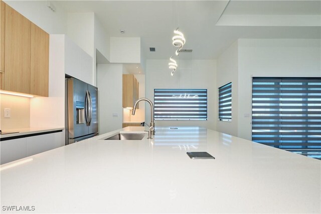 kitchen with modern cabinets, a sink, light countertops, and stainless steel fridge