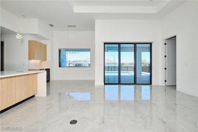 unfurnished living room featuring a raised ceiling, visible vents, and marble finish floor