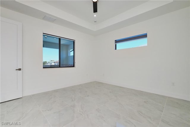 unfurnished room featuring ceiling fan, baseboards, and a raised ceiling