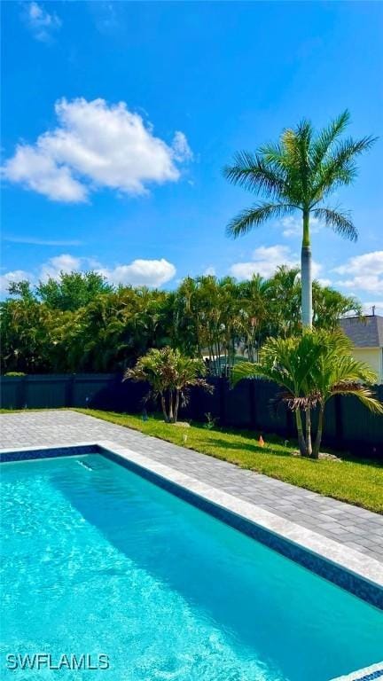 view of swimming pool with a lawn, fence, and a fenced in pool