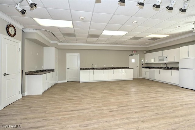 677 12th Ave S Unit 677, Naples, FL 34102 - kitchen with dark countertops, a sink, light wood-style floors, white appliances, and white cabinetry