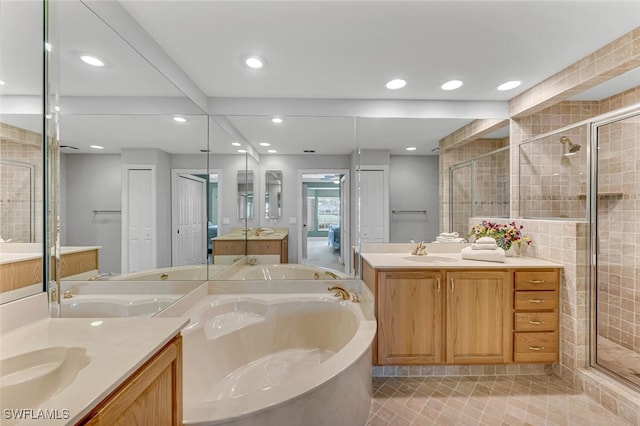 full bath featuring recessed lighting, two vanities, a sink, a stall shower, and a garden tub