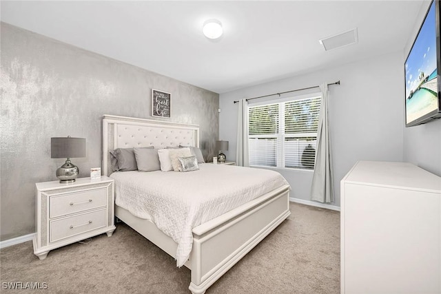 bedroom with baseboards, attic access, and light carpet