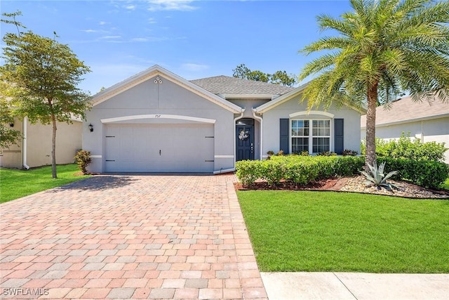 ranch-style home featuring a garage, a front yard, decorative driveway, and stucco siding