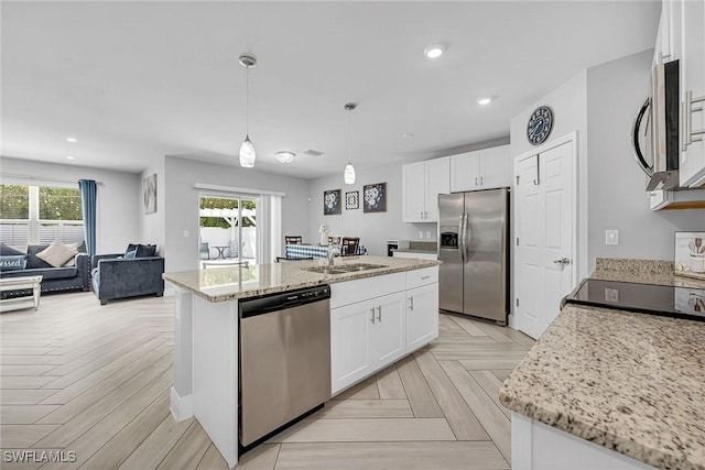 kitchen featuring an island with sink, white cabinetry, a sink, and appliances with stainless steel finishes