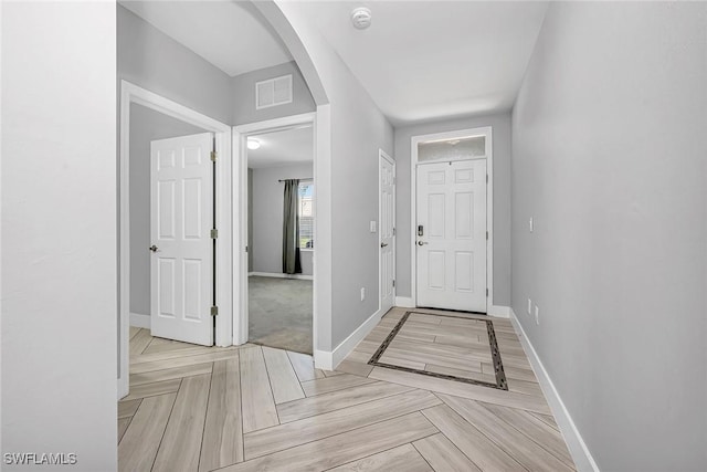 entryway with baseboards, visible vents, and arched walkways