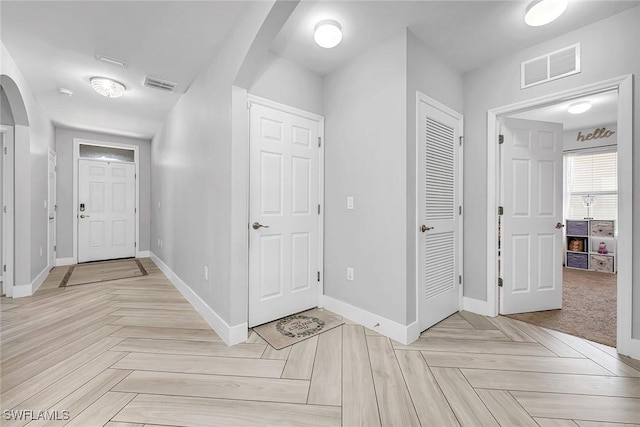 hall featuring arched walkways, baseboards, and visible vents