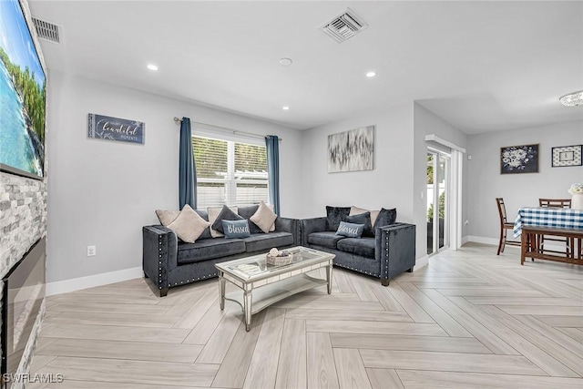 living room with baseboards, visible vents, and recessed lighting