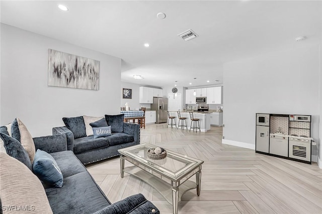 living room featuring baseboards, visible vents, and recessed lighting