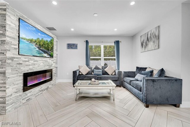 living area with a stone fireplace, baseboards, visible vents, and recessed lighting