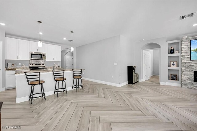 kitchen with arched walkways, visible vents, stainless steel appliances, and built in features