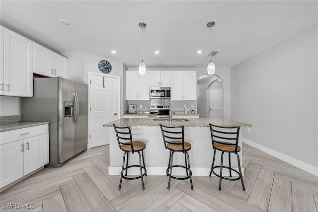 kitchen featuring white cabinets, visible vents, a kitchen bar, appliances with stainless steel finishes, and a sink