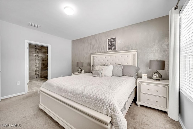 bedroom featuring light carpet, baseboards, visible vents, and ensuite bathroom