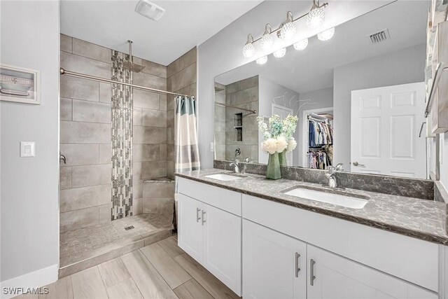 full bathroom with visible vents, a sink, a spacious closet, and a shower stall
