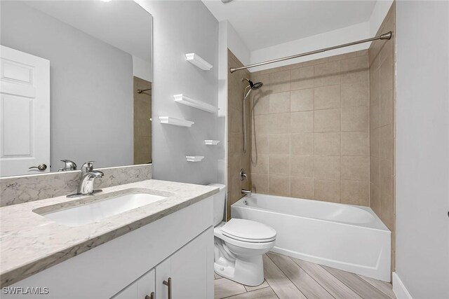 bathroom with toilet, vanity, shower / tub combination, and wood finish floors