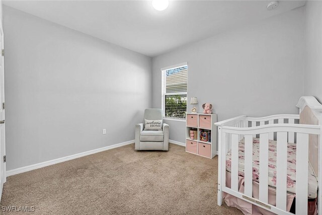 carpeted bedroom with baseboards and a crib