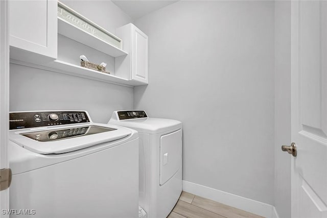laundry area featuring independent washer and dryer, cabinet space, and baseboards