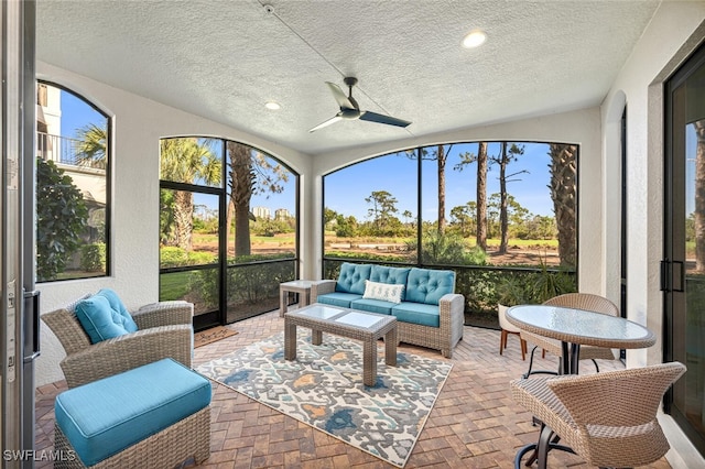 sunroom featuring an outdoor hangout area, a ceiling fan, and plenty of natural light