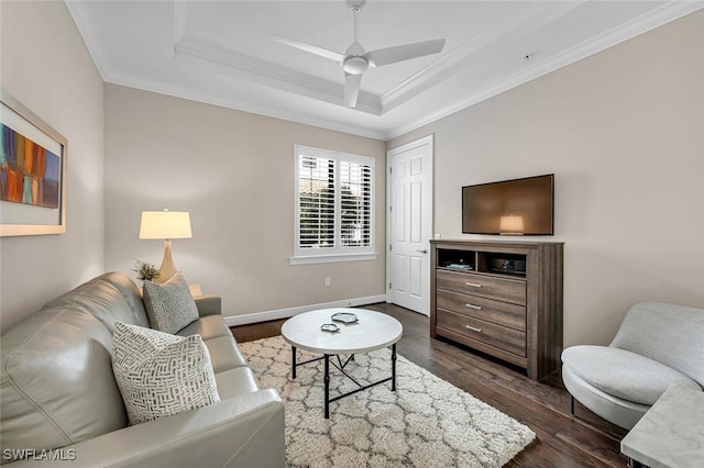 living room with baseboards, ornamental molding, a ceiling fan, a raised ceiling, and dark wood-style floors
