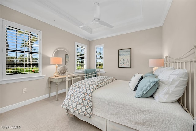 carpeted bedroom with a tray ceiling, baseboards, crown molding, and a ceiling fan