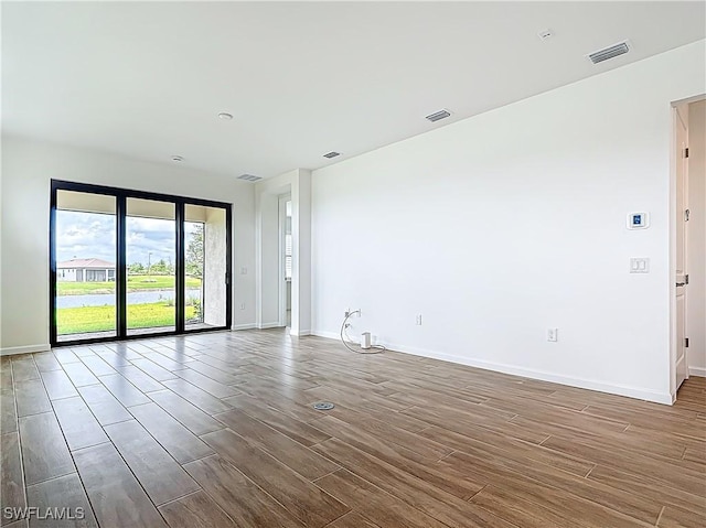 unfurnished room featuring visible vents, baseboards, and wood finished floors