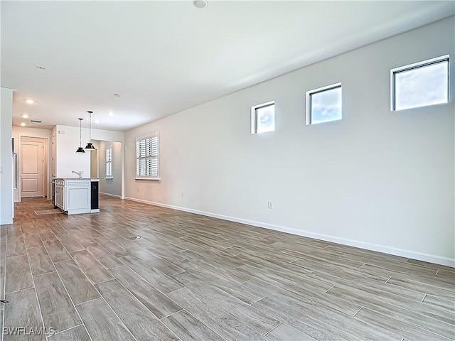 unfurnished living room featuring baseboards, a sink, wood tiled floor, and recessed lighting