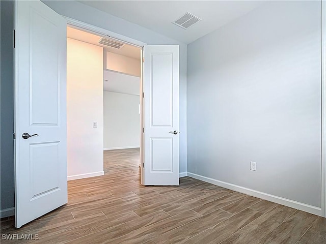 unfurnished bedroom with wood finished floors, baseboards, and visible vents