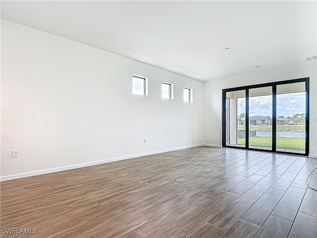 unfurnished room with visible vents, baseboards, and wood finished floors