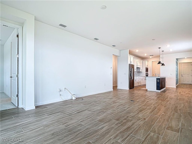 unfurnished living room with visible vents, baseboards, wood tiled floor, and recessed lighting