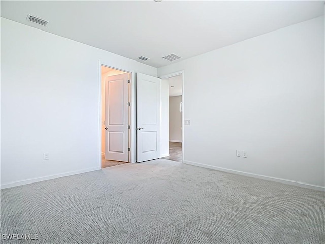 carpeted spare room with visible vents and baseboards