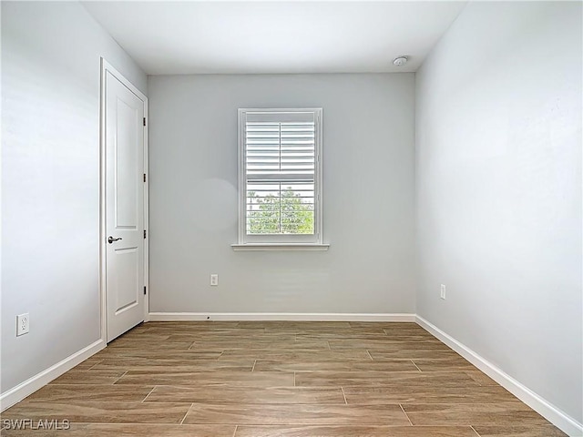 spare room featuring baseboards and wood finished floors