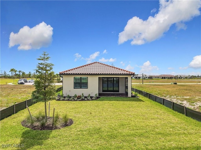 rear view of property with a tiled roof, fence, and a lawn