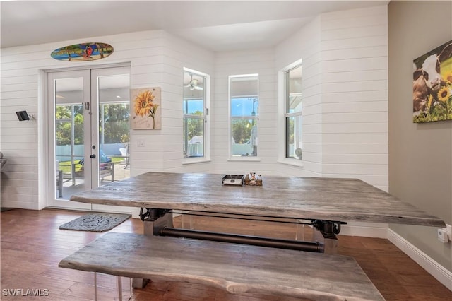 dining area with baseboards, french doors, wood walls, and wood finished floors