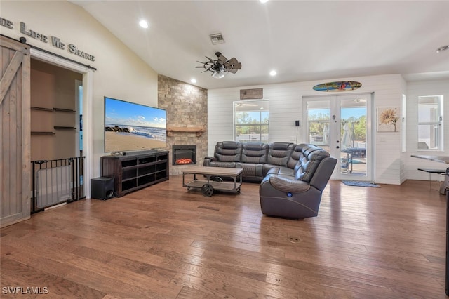 living room featuring a barn door, a ceiling fan, hardwood / wood-style floors, and visible vents