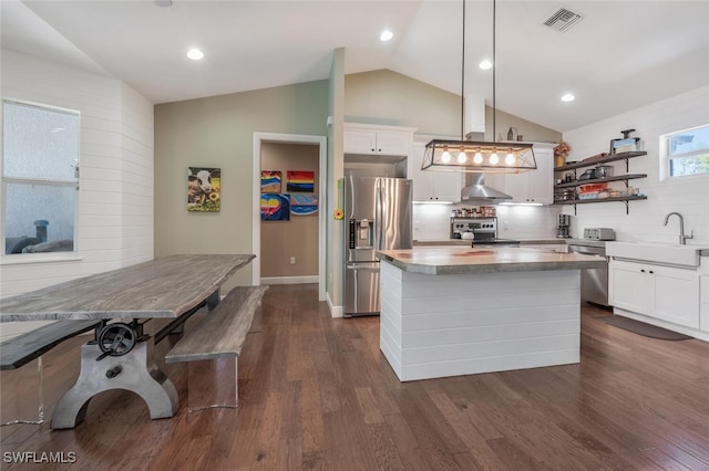 kitchen featuring appliances with stainless steel finishes, a sink, visible vents, a center island, and vaulted ceiling