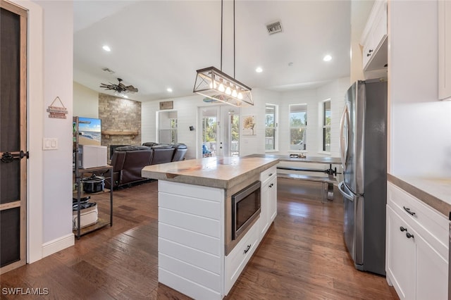 482 10th Ave NW, Naples, FL 34120 - kitchen with stainless steel appliances, white cabinetry, a center island, a stone fireplace, and recessed lighting