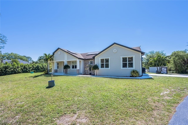 single story home featuring a front lawn, a patio area, and solar panels