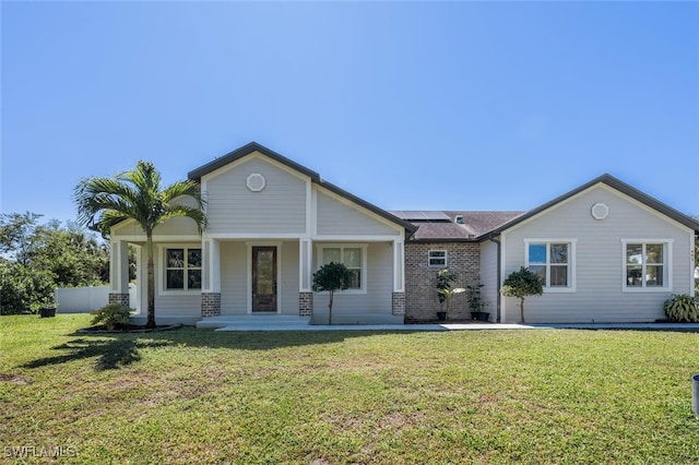 single story home featuring covered porch, solar panels, and a front lawn