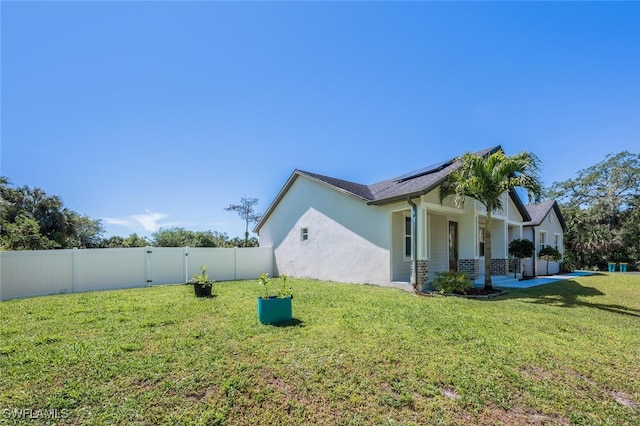view of property exterior with a fenced backyard, a yard, and solar panels