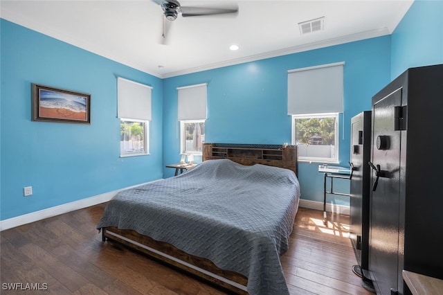bedroom featuring a ceiling fan, visible vents, crown molding, baseboards, and hardwood / wood-style floors