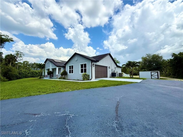 482 10th Ave NW, Naples, FL 34120 - ranch-style home with asphalt driveway, a garage, a front lawn, and a storage unit