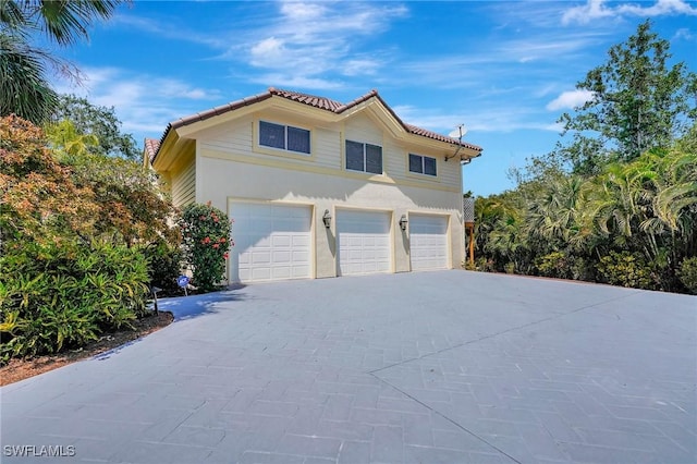 27231 Lakeway Ct, Bonita Springs, FL 34134 - view of home's exterior with stucco siding, an attached garage, a tiled roof, and driveway