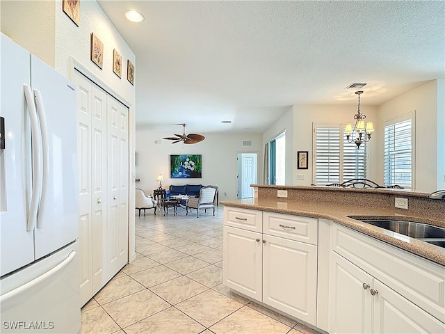 20716 Tisbury Ln, North Fort Myers, FL 33917 - kitchen featuring visible vents, hanging light fixtures, a sink, freestanding refrigerator, and white cabinetry