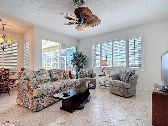 20716 Tisbury Ln, North Fort Myers, FL 33917 - living room with baseboards, a textured ceiling, light tile patterned flooring, visible vents, and ceiling fan with notable chandelier