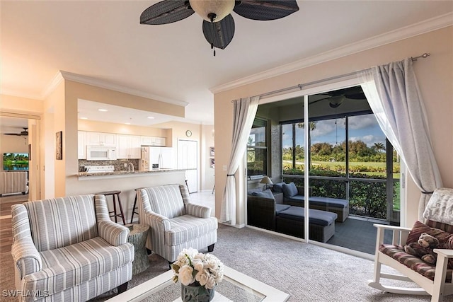 living area with ornamental molding, ceiling fan, and carpet flooring